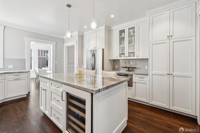 kitchen featuring appliances with stainless steel finishes, decorative light fixtures, white cabinetry, beverage cooler, and light stone counters