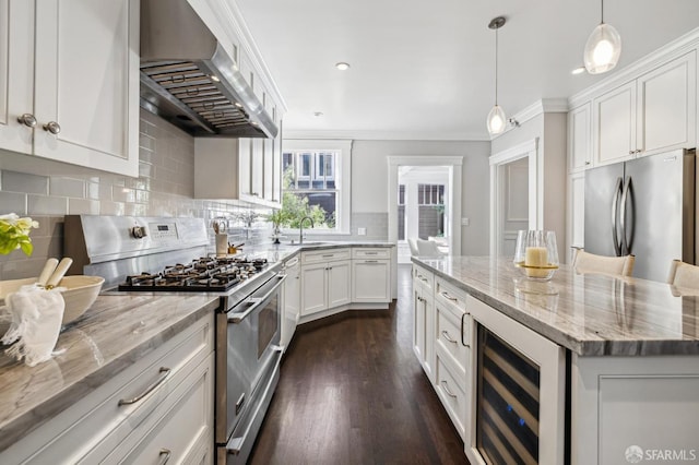 kitchen with appliances with stainless steel finishes, white cabinetry, beverage cooler, a center island, and wall chimney exhaust hood