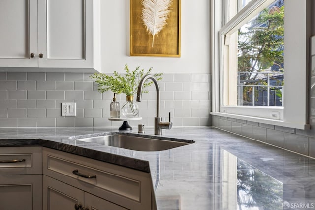 kitchen with white cabinetry, sink, a wealth of natural light, and stone countertops