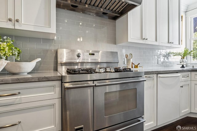 kitchen featuring wall chimney exhaust hood, range with two ovens, white cabinetry, stone counters, and decorative backsplash