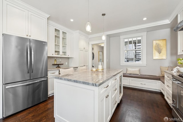 kitchen featuring light stone counters, hanging light fixtures, stainless steel fridge, a kitchen island, and white cabinets