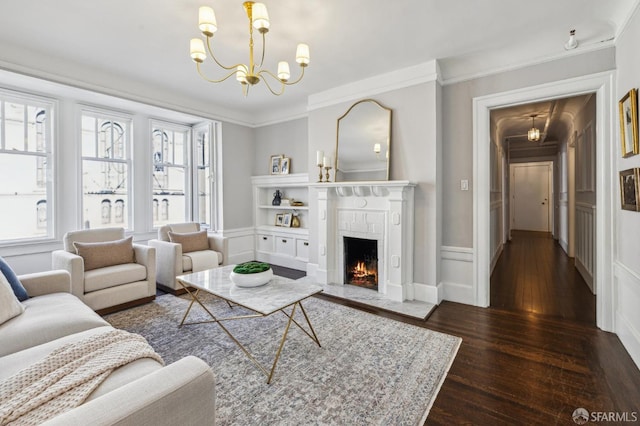 living room featuring crown molding, dark hardwood / wood-style floors, a chandelier, and a fireplace