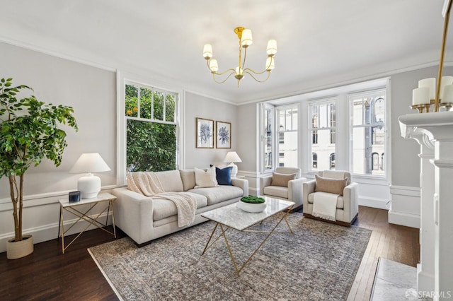 living room with dark wood-type flooring, a fireplace, crown molding, and a chandelier