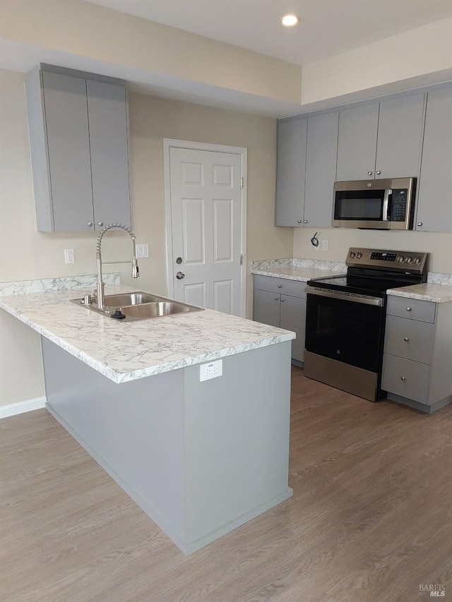 kitchen featuring sink, gray cabinets, kitchen peninsula, and appliances with stainless steel finishes