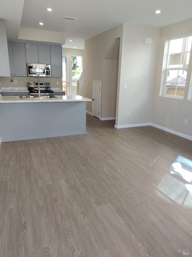 kitchen featuring appliances with stainless steel finishes, gray cabinets, sink, and light wood-type flooring