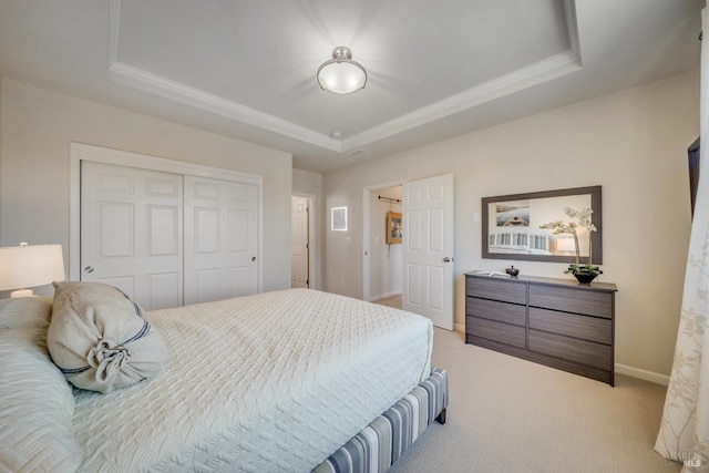 bedroom with light carpet, a tray ceiling, and a closet