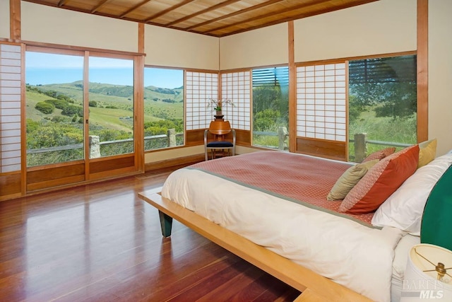 bedroom with a mountain view, wooden ceiling, and hardwood / wood-style floors