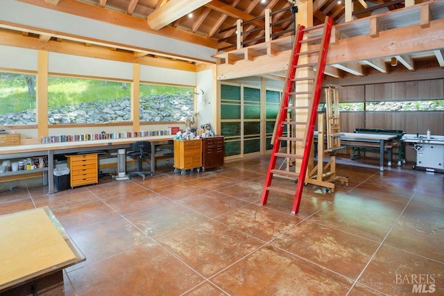 misc room with beamed ceiling, tile patterned floors, and a workshop area