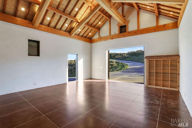 empty room featuring wood ceiling, beam ceiling, high vaulted ceiling, and dark tile patterned floors