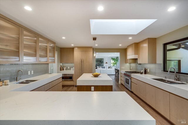 kitchen with appliances with stainless steel finishes, a center island, sink, and light brown cabinetry