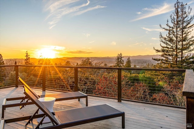 balcony at dusk featuring a deck with mountain view