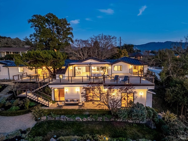 back house at dusk featuring a mountain view, a patio area, and a balcony