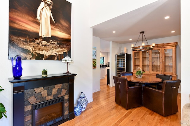 dining space featuring recessed lighting, an inviting chandelier, baseboards, light wood-style floors, and a stone fireplace