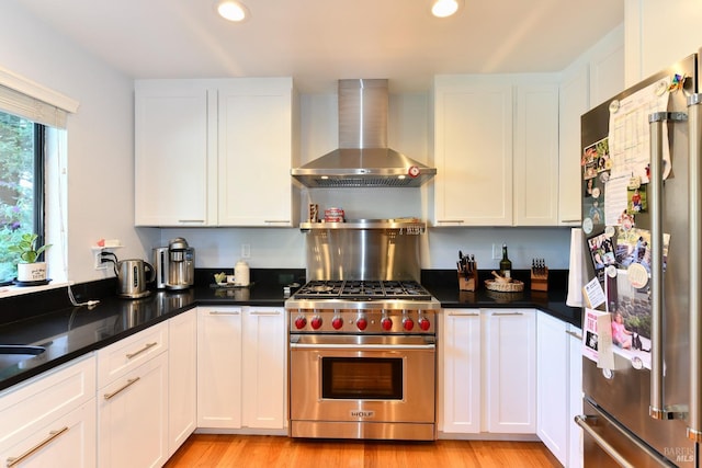 kitchen featuring white cabinetry, wall chimney exhaust hood, light wood-style floors, and appliances with stainless steel finishes