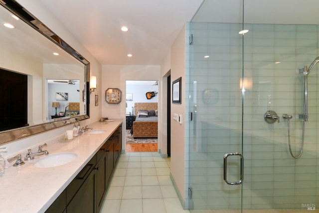 ensuite bathroom with connected bathroom, tile patterned floors, a sink, a shower stall, and double vanity