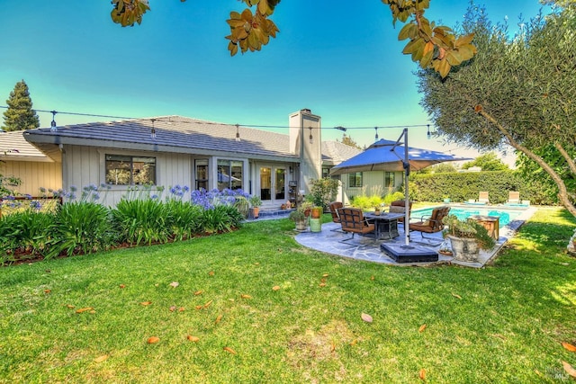 back of house with a chimney, a patio, french doors, a fenced in pool, and a lawn