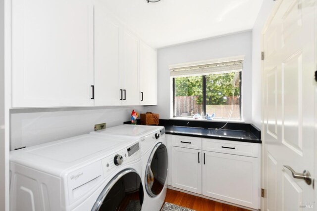 clothes washing area with washer and clothes dryer, wood finished floors, and cabinet space