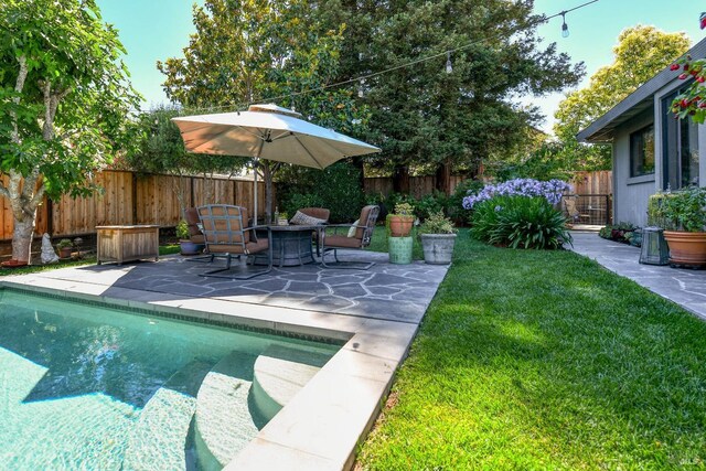 view of swimming pool featuring a fenced backyard, an outdoor fire pit, a fenced in pool, a patio area, and a lawn