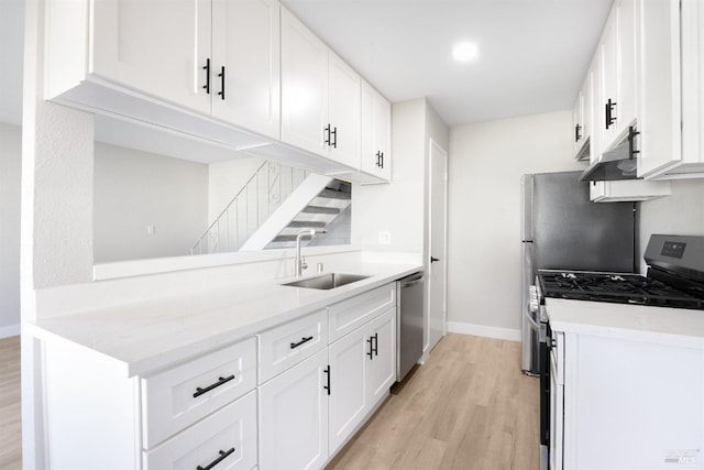 kitchen featuring sink, white cabinets, light hardwood / wood-style floors, stainless steel appliances, and light stone countertops