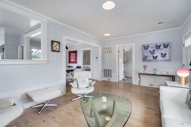 living room with crown molding and light hardwood / wood-style flooring