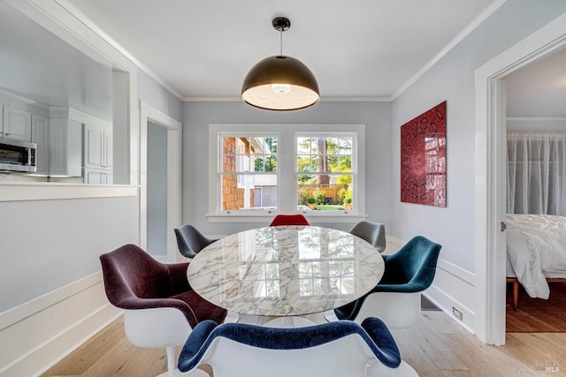 dining space featuring ornamental molding and light hardwood / wood-style flooring