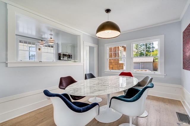 dining space featuring ornamental molding and light wood-type flooring