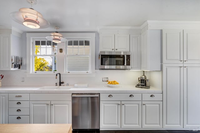 kitchen with pendant lighting, sink, white cabinetry, stainless steel appliances, and tasteful backsplash