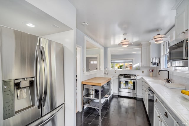 kitchen featuring white cabinetry, appliances with stainless steel finishes, sink, and tile counters