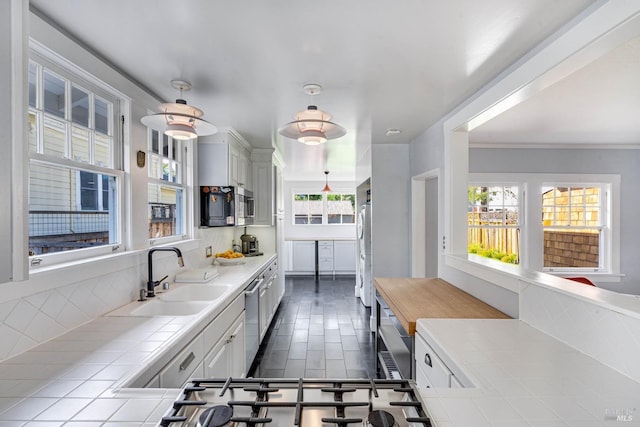 kitchen featuring sink, stainless steel appliances, tasteful backsplash, white cabinets, and tile countertops