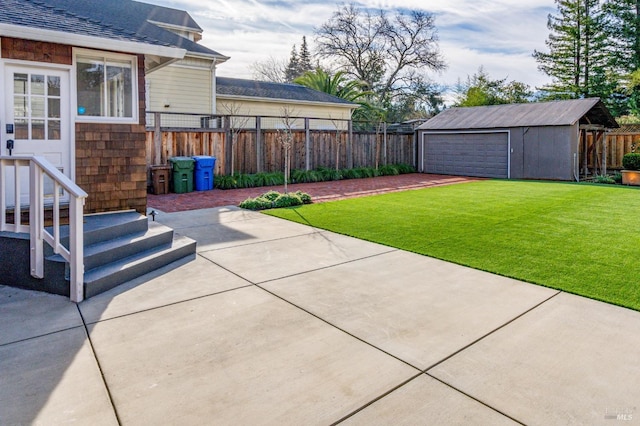 view of yard featuring a garage, an outbuilding, and a patio area