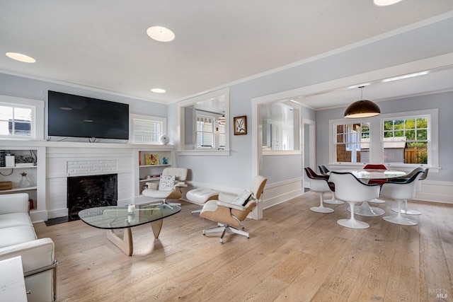 living room featuring ornamental molding, a brick fireplace, and light wood-type flooring