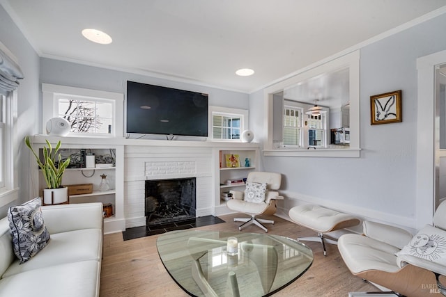 living room with hardwood / wood-style flooring, ornamental molding, and a fireplace