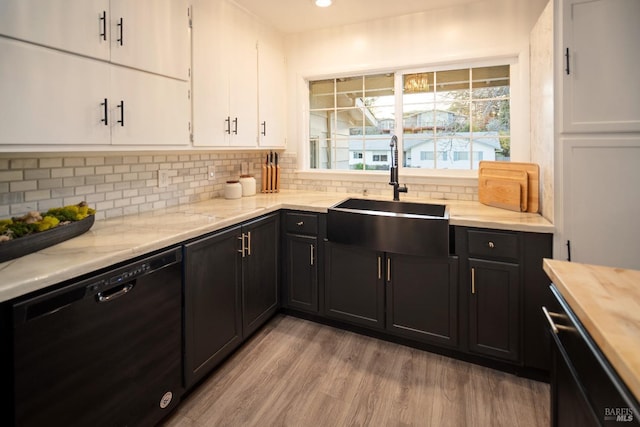 kitchen with black dishwasher, sink, white cabinets, backsplash, and light hardwood / wood-style flooring