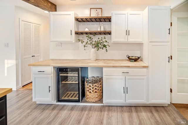 bar featuring wine cooler, white cabinetry, wooden counters, and light hardwood / wood-style flooring