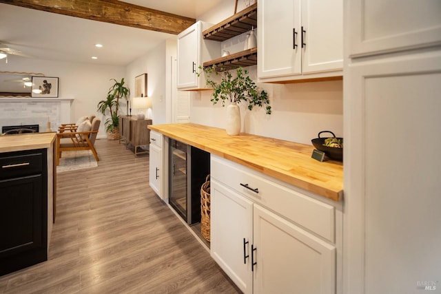 bar featuring butcher block countertops, ceiling fan, beverage cooler, light hardwood / wood-style floors, and white cabinets