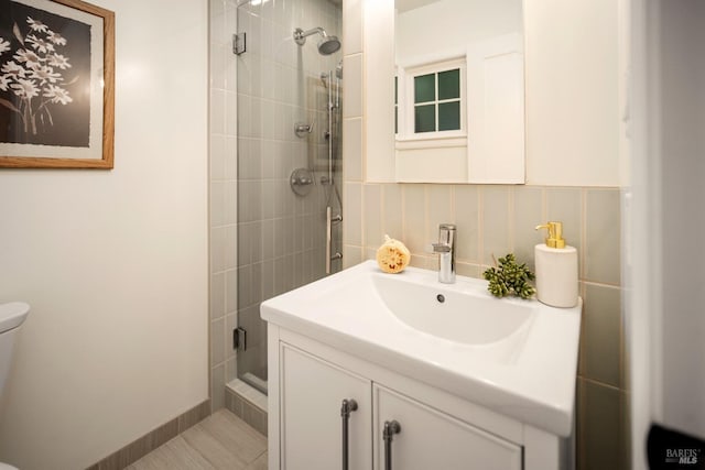 bathroom featuring vanity, a tile shower, and toilet