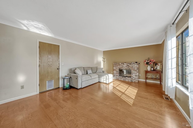 unfurnished living room with ornamental molding, a stone fireplace, and light hardwood / wood-style floors