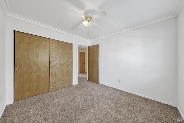 unfurnished bedroom with crown molding, carpet floors, ceiling fan, and a closet