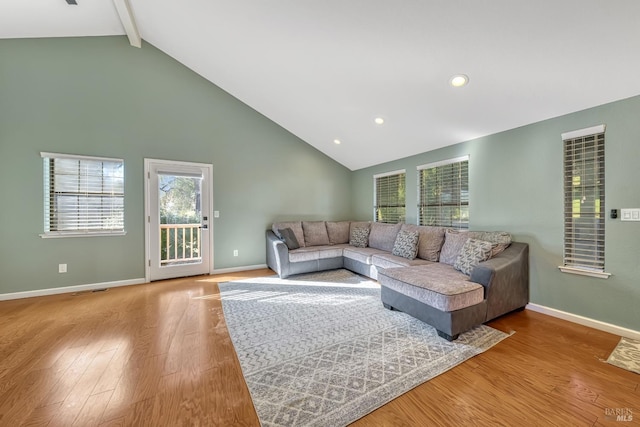 living room featuring light wood-type flooring and vaulted ceiling with beams