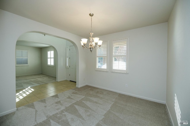 spare room with light carpet and a chandelier