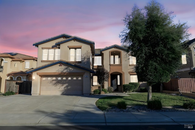 view of front of house with an attached garage, fence, concrete driveway, and stucco siding