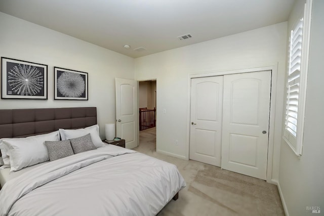 bedroom featuring light colored carpet, a closet, visible vents, and baseboards