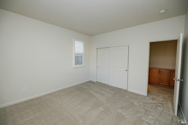 unfurnished bedroom featuring light carpet, a closet, and baseboards