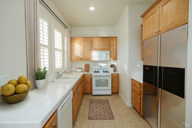 kitchen featuring light tile patterned flooring, white appliances, tile counters, and sink