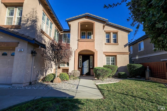 view of front of property with a garage, a front lawn, a tile roof, and stucco siding