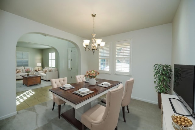 tiled dining room with arched walkways, baseboards, carpet flooring, and a notable chandelier