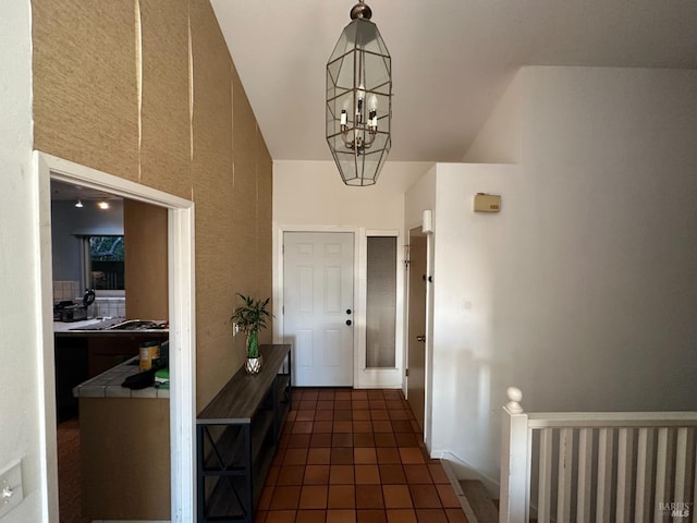 interior space featuring dark tile patterned floors, vaulted ceiling, and a notable chandelier