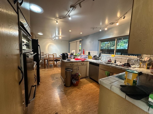 kitchen with tasteful backsplash, tile counters, stainless steel dishwasher, and kitchen peninsula