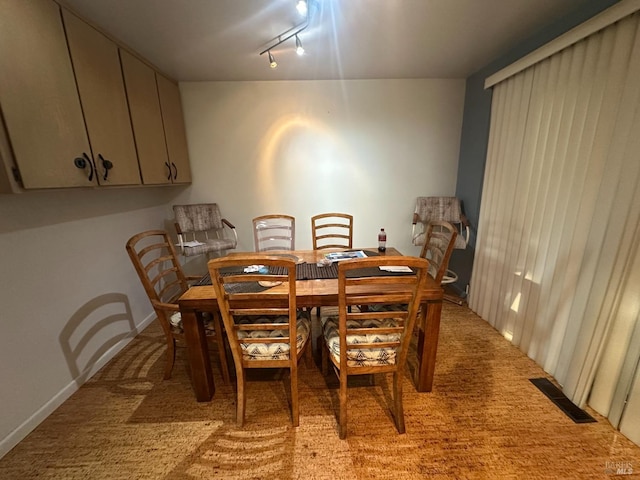 dining room with rail lighting and light carpet