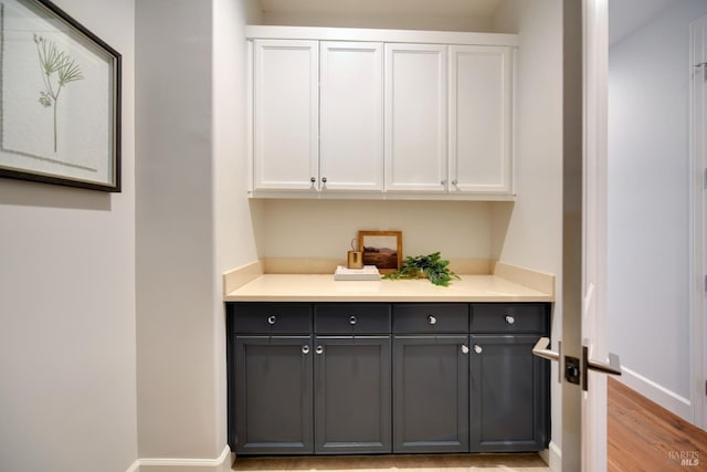 bar featuring gray cabinets, light wood-type flooring, and white cabinets